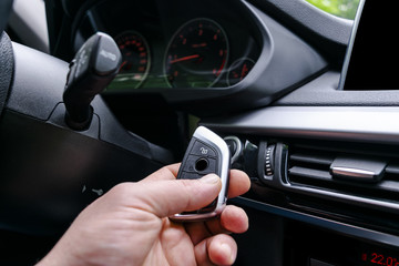 Closeup inside vehicle of man hand holding wireless key ignition. Start engine key. Hand holding car key remote. Modern car background. Interior details. Car detailing