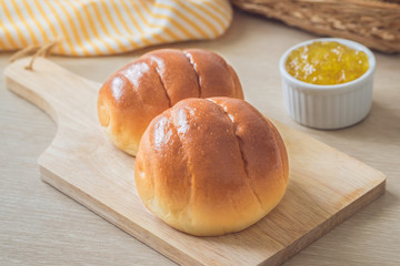 Round bun, bread rolls on wooden plate and pineapple jam