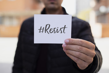 man showing a note with the hashtag resist