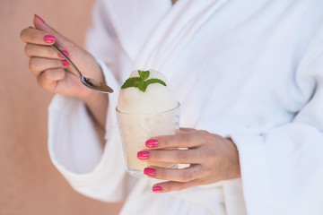 Happy woman in bathrobe sitting and holding an oxygen foam cocktail in SPA center