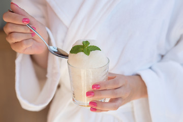 Happy woman in bathrobe sitting and holding an oxygen foam cocktail in SPA center