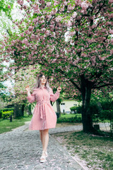 Young Woman in Red Striped Dress Walking in Garden