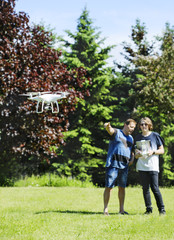 Fototapeta premium Father and son on summer day flying drone on countryside.