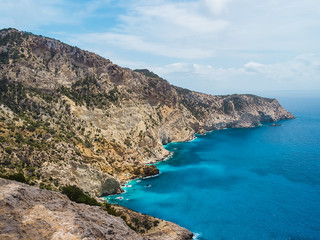 Fototapeta premium Acantilados, mar mediterraneo turquesa y montañas, del parque natural de Cala D´hort, en Ibiza, España. Es una ruta de trekking que lleva hasta la Torre des savinar para poder contemplar Es Vedrá.