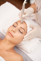 Obraz na płótnie Canvas Relaxed woman lying in beauty salon and having anti-wrinkle therapy on her forehead