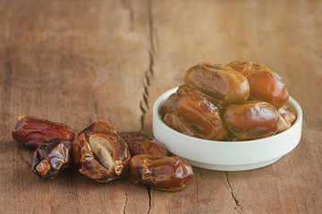 Khalas date palm on wood table in side view with copy space for background or wallpaper. Dates fruit is food for Ramadan or medjool. Delicious dried fruit with sweet taste and have high fiber.