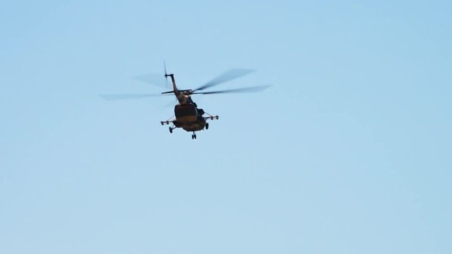 A tracking shot of a flying transport helicopter. The chopper is in camouflage paint.