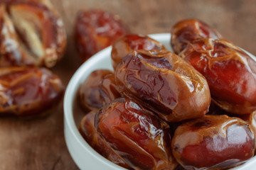 Khalas date palm on wood table in close up with copy space for background or wallpaper. Dates fruit is food for Ramadan or medjool. Delicious dried fruit with sweet taste and have high fiber.