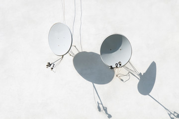 Two satellite dishes on white plastered wall