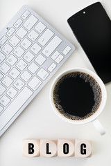 Würfel mit dem Wort BLOG am Arbeitsplatz mit Tastatur und Kaffee