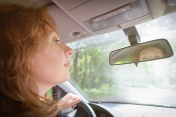 Woman looking at the mirror in her car
