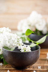 Delicate and beautiful flowers of white lilac in exquisite ceramic cups on a wooden background.