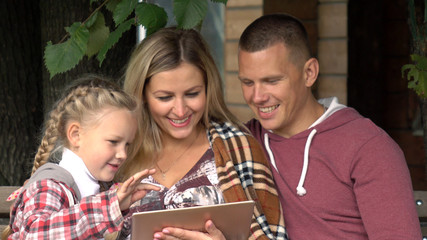 Family reading a book.Pair shows the child a book on the background of a country house.