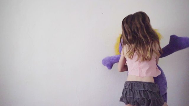 Girl jumping while hugging a stuffed animal in slow motion