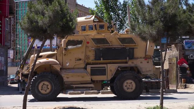 A wide shot of an armored truck parked in the city of Kabul.