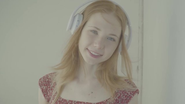 Beautiful red-haired woman with headphones listen to music, color profile Slog3