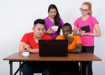 Studio shot of diverse group of multi ethnic friends using lapto