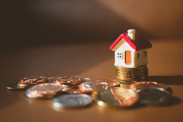 Miniature house on stack coins using as business and financial concept