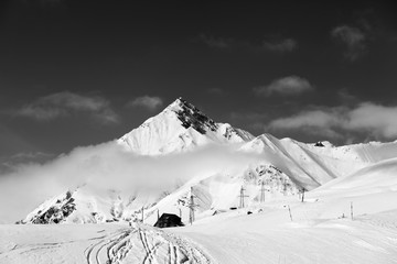 Black and white view on snowy ski slope and mountains