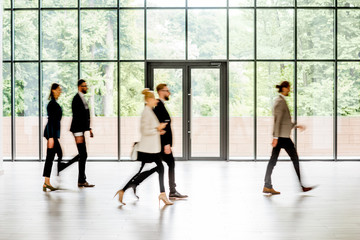 Business people walking at the modern hall on the window background indoors. long exposure image...
