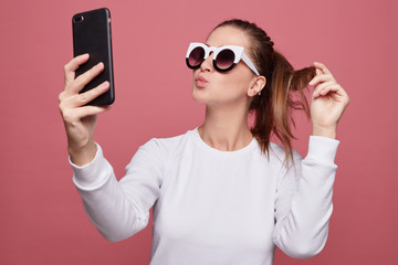 Portrait of beautiful redhead lady wearing white long sleeved t shirt and fashionable spectacles,...