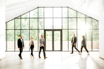 Business people at the spacious modern hall with big window overlooking on the park. Wide view with copy space