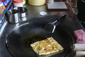 Roti eggs fried (thai word) in a night market street, Indian food, Chapati flatbread, roti canai, dal, curry, teh tarik or pulled tea, acar. Famous indian cuisine