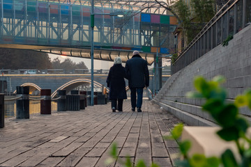 Back view of adult european couple walking near the river on sunset