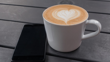 technology, business and modern life concept- close up of smartphone and coffee cup on table at cafe
