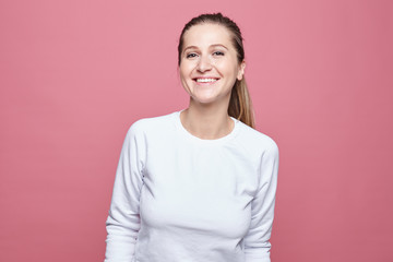 Fototapeta premium Happy woman laughing. Closeup portrait of woman with perfect smile and white teeth, looking happy, isolated over pink wall background. Positive human emotion, facial expression, body language conept.