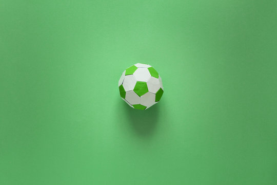 Paper soccer ball on soccer field or green background. Origami. Paper craft. Soccer game concept.