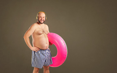 Funny fat naked man with a circle for swimming in summer on a background for text.