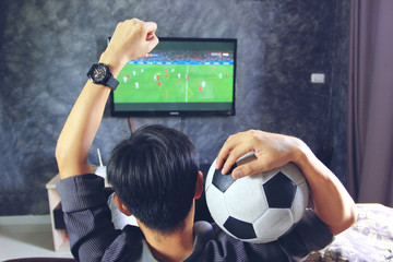Entertainment concept, Selective focus of happy male hold the old football with looking at sport on tv at home