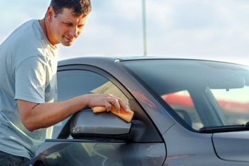 man cleaning car with microfiber cloth, car detailing.