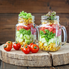 Two glass jars with vegetable salad and cherry tomatoes. Healthy