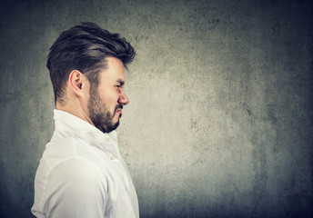 Profile portrait of a bearded man with grimace of disgust