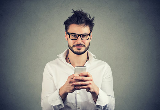 Happy hipster man in glasses using a smartphone