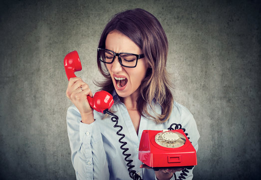 angry enraged business woman yelling at the red telephone