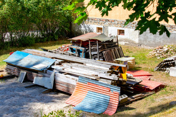 Gently stacked old building materials in courtyard of private house.Plastic and asbestos...