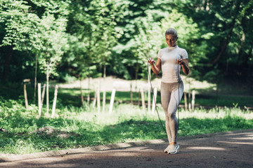 Portrait of Fit Young Woman with Jump Rope in Park. Fitness Female Doing Workout Outdoors in Park on Sunny Day.