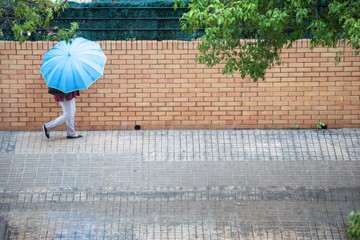 Woman with umbrella running through the streets while heavy rain falls
