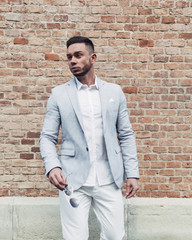 Young Guy with Beard and with Glasses in Stylish Suit Posing on the Street in the Sunlight