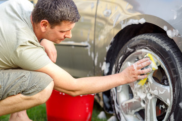Fototapeta na wymiar Men cleaning wheels with a sponge and foam.