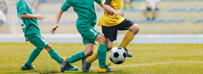 Obraz premium Young Junior Football Match. Players Running and Kicking Football Ball