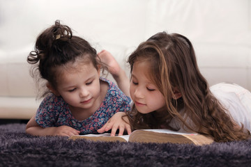 Two Little Sisters Reading Bible on Carpet