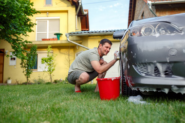 Car washing. Man cleaning his car using sponge and foam.