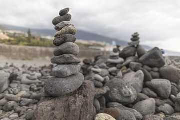 Fototapeta na wymiar Puerto de la Cruz. Stone piles ( Cairns) on Playa Jardin, Peurto de la Cruz, Tenerife, Canary Islands, Spain. Selfmade rock-monument at the beach of Puerto de la Cruz Tenerife.