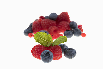 Himbeern Heidelbeeren und Johannesbeeren mit Minzblatt auf weissem Hintergrund