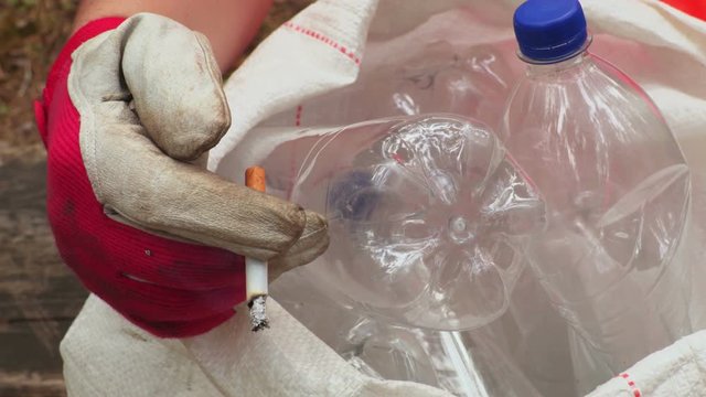 Workers hand with cigarette on plastic bottles in bag
