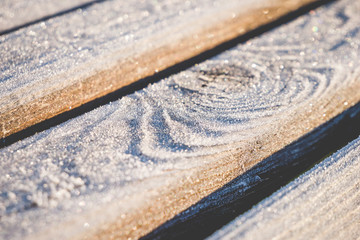 Close up of wooden planks covered with sparkling hoar frost. Shallow depth of field. For wallpaper, background